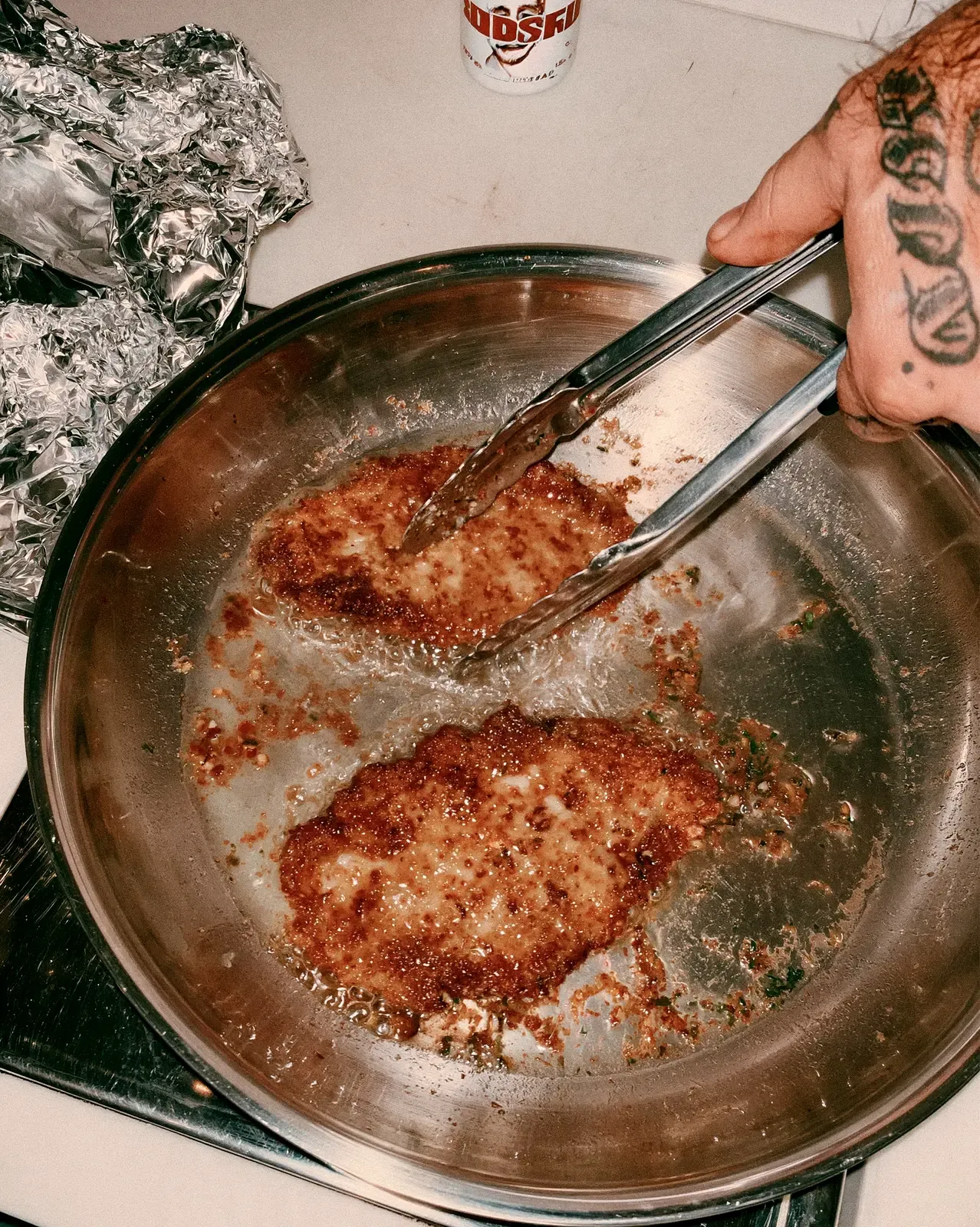 Bras tatoué qui retourne une escalope dans une poêle