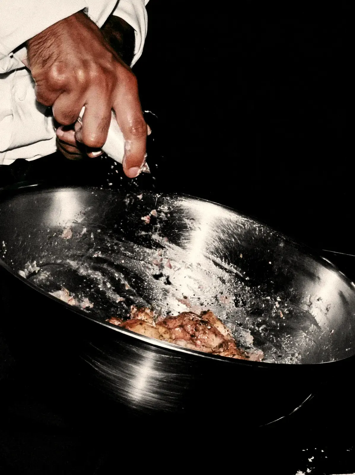 Main qui jette de la roquette dans une bassine en inox