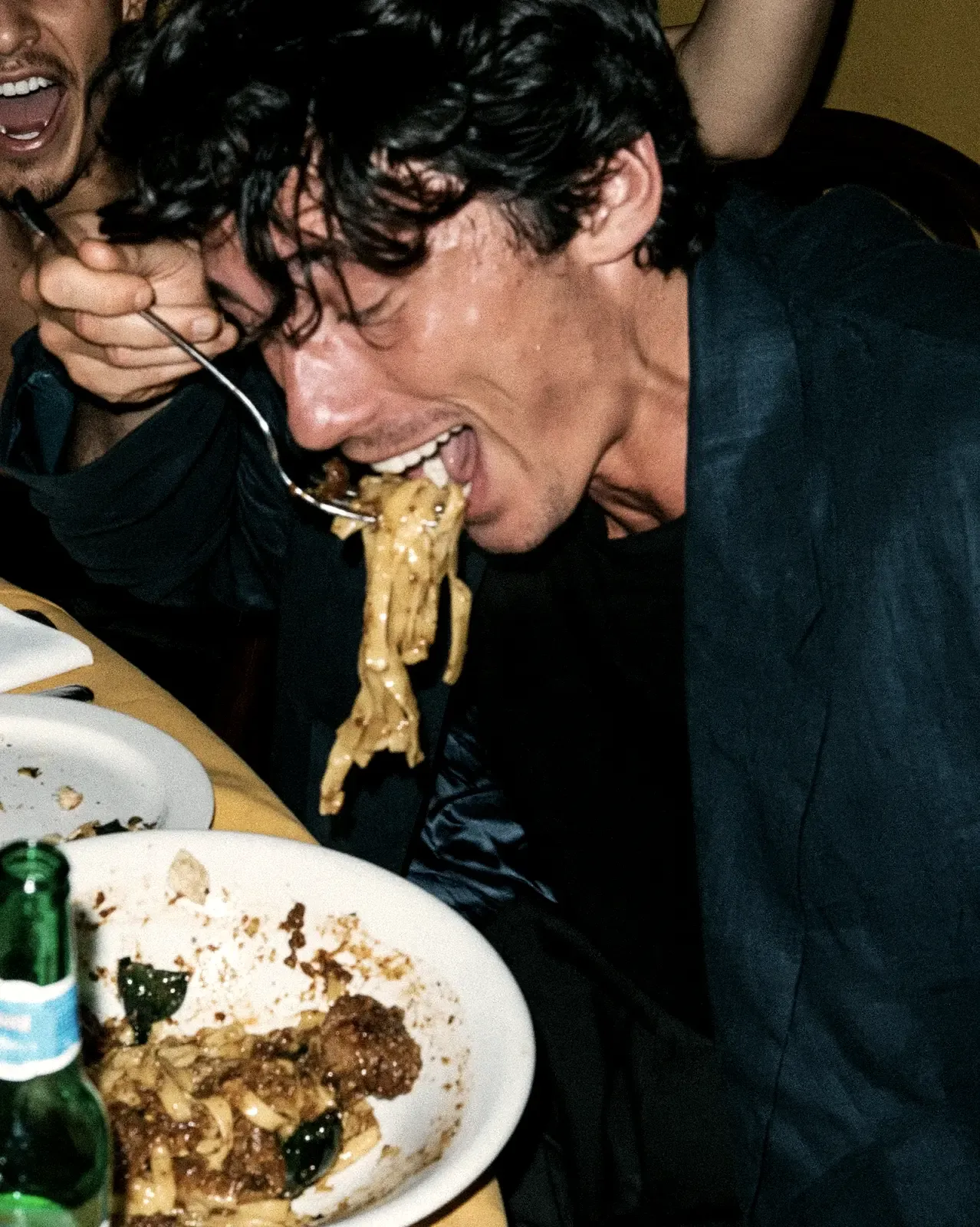 Client d'un restaurant qui mange des pâtes avec gourmandise, photo au flash