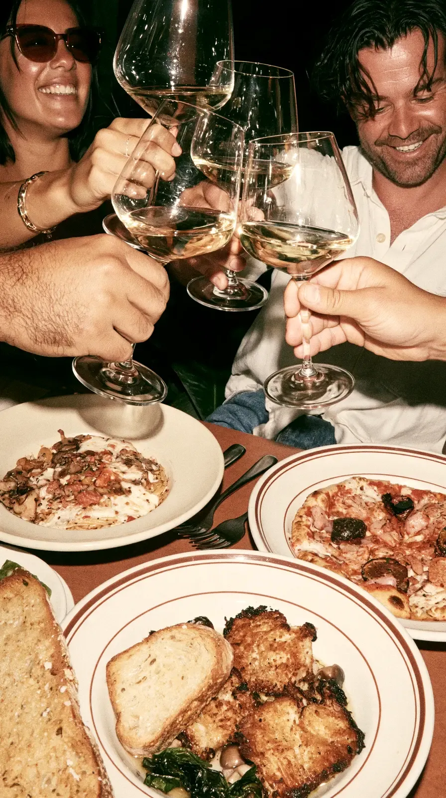Des convives trinquent au-dessus d'une table de brasserie