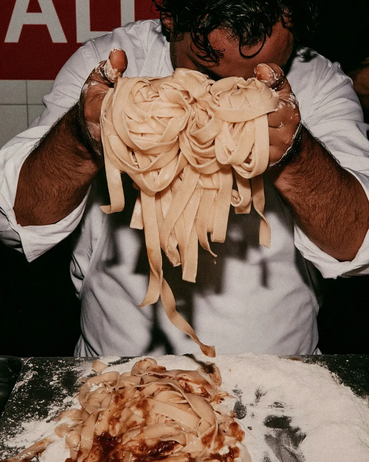 Cuisinier qui soulève des tagliatelles fraîches farinées